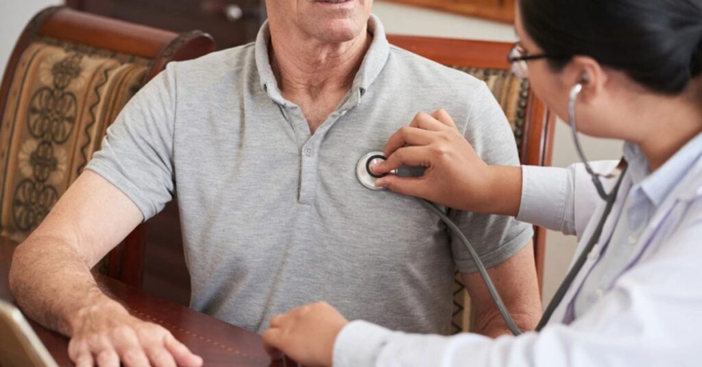 "Young Indian man clutching chest, highlighting rise in heart attacks among youth."