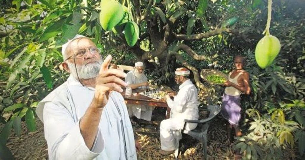 Kalimullah Khan standing beside his unique mango tree that bears over 350 varieties in his orchard in Malihabad, Uttar Pradesh